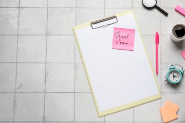Yazılı yapışkan not FINAL Sınav Defteri, not defteri, büyüteç ve beyaz karo zemin üzerinde bir fincan kahve