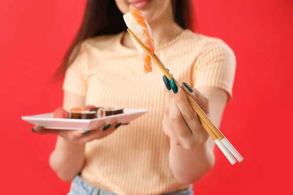 Mujer Joven Con Rollos Sushi Palillos Sobre Fondo Rojo Primer — Foto de Stock
