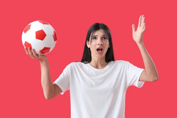 Šokovaná Mladá Žena Fotbalovým Míčem Červeném Pozadí — Stock fotografie