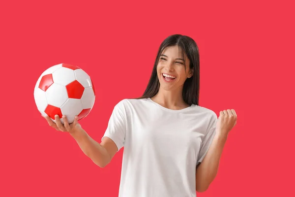 Kırmızı Arka Planda Futbol Topu Olan Mutlu Genç Bir Kadın — Stok fotoğraf