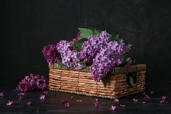 Wicker box of beautiful lilac flowers on black table