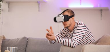 Young man using VR glasses at home