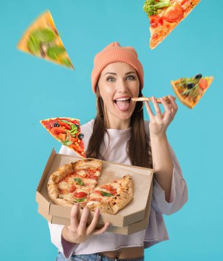 Güzel genç bayan mavi arka planda lezzetli pizzalar yiyor.
