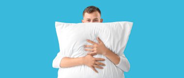 Açık mavi arka planda yumuşak yastıklı genç adam