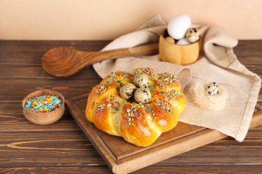 Lezzetli İtalyan Paskalya ekmeği, renkli süsler ve ahşap masada yumurtalar.