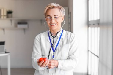 Klinikte küçük kırmızı kalbi olan olgun bir kadın kardiyolog.