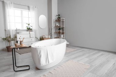 Küveti, masası ve pencerenin yanındaki çekmeceleri olan hafif banyonun içi.