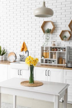 Mutfağın içindeki masada çiçek açan vazo.