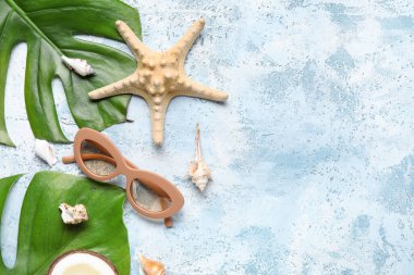Renkli arka planda şık güneş gözlüklü, palmiye yapraklı, deniz yıldızı ve deniz kabuklu kompozisyon