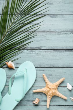 Parmak arası terlik, deniz yıldızı, deniz kabuğu ve ahşap arka planda palmiye yaprağı kompozisyonu