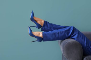 Mavi arka planda, yüksek topuklu kadın bacakları.