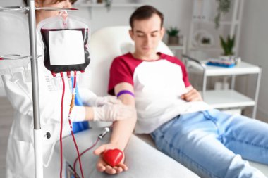 Top tutan genç adam kliniğe kan bağışlıyor.