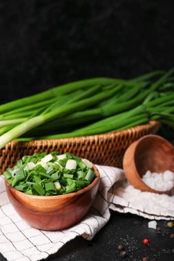 Koyu arkaplanda taze kesilmiş yeşil soğanlı kase.