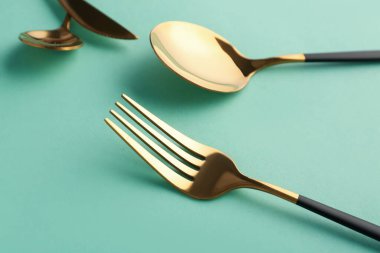 Yeşil arka planda şık çatal ve kaşık