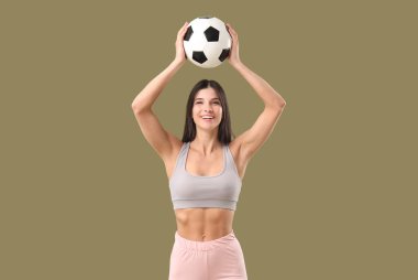 Futbol topunun arka planında spor yapan genç bir kadın.
