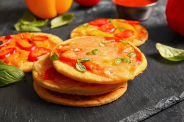 Siyah arkaplanda farklı lezzetli mini pizzalar olan tahta