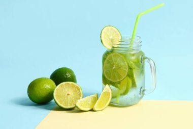 Mason kavanozu soğuk mojito ve renkli arka planda limon.