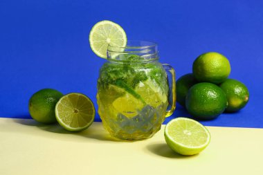 Mason kavanozu soğuk mojito ve renkli arka planda limon.