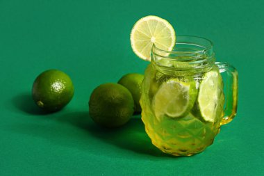 Mason kavanozu soğuk mojito ve yeşil arka planda limon.