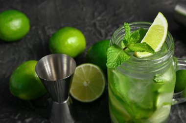 Mason kavanozu soğuk mojito ve limon siyah masada.