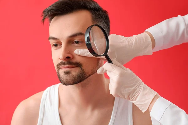 Dermatolog Undersöka Födelsemärke Ung Man Med Förstoringsglas Röd Bakgrund Närbild — Stockfoto