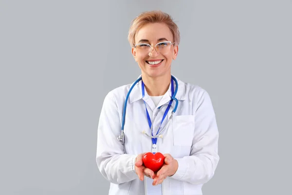 Dojrzałe Kobieta Kardiolog Małym Czerwonym Sercem Szarym Tle — Zdjęcie stockowe