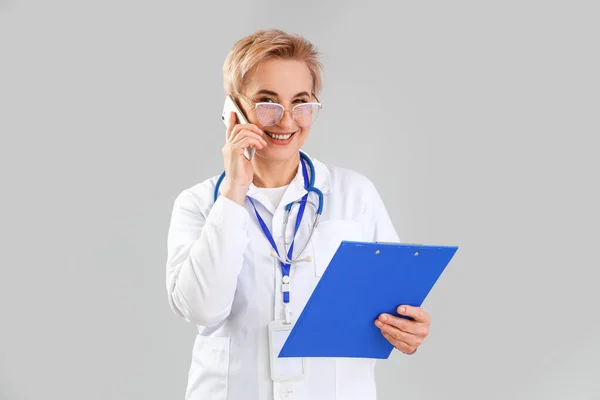 Dojrzałe Kobieta Lekarz Mówi Przez Telefon Szarym Tle — Zdjęcie stockowe
