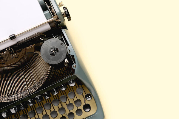 Винтажная пишущая машинка с чистым листом бумаги на желтом фоне