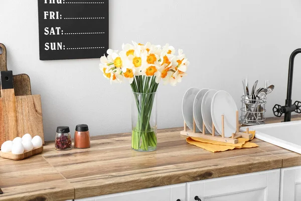 花瓶ともに開花ナルシシズム花上の木製のカウンターで現代的なキッチンのインテリア — ストック写真