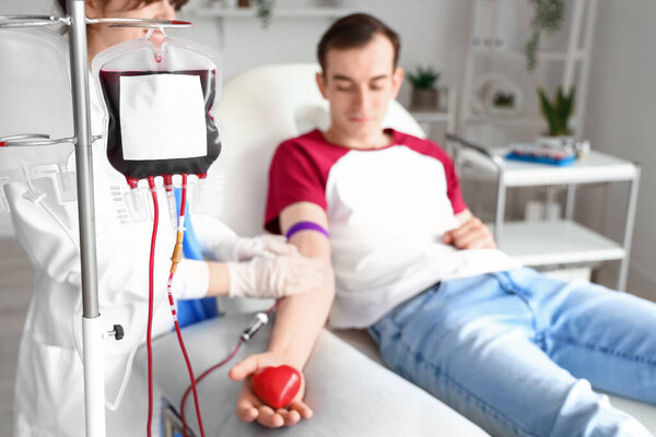 Young man with grip ball donating blood in clinic