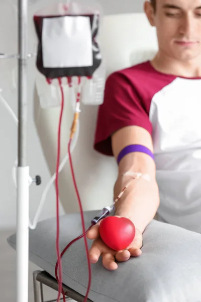 Stock image Young man with grip ball donating blood in clinic, closeup