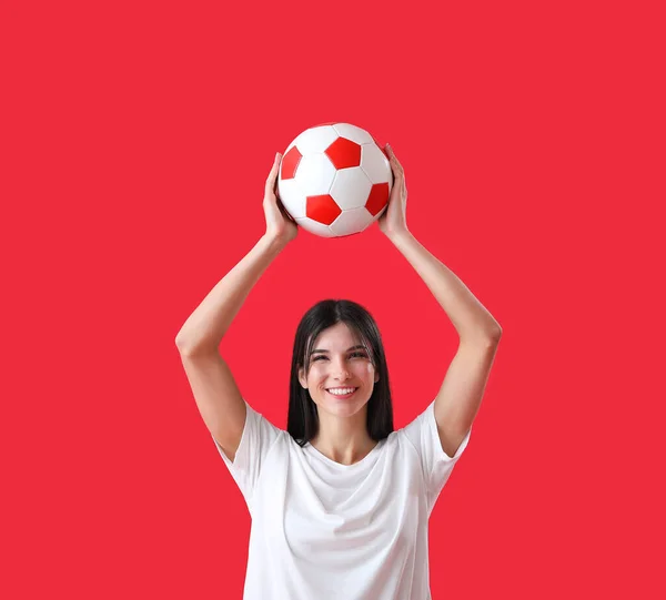 幸せな若いです女性とともにサッカーボール上の赤い背景 — ストック写真