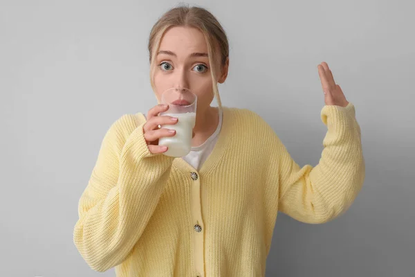 灰色の背景に牛乳を飲む若い女性 — ストック写真