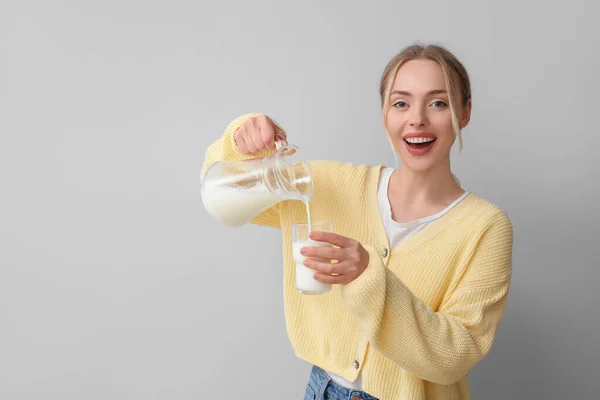 Νεαρή Γυναίκα Ρίχνει Γάλα Ποτήρι Γκρι Φόντο — Φωτογραφία Αρχείου