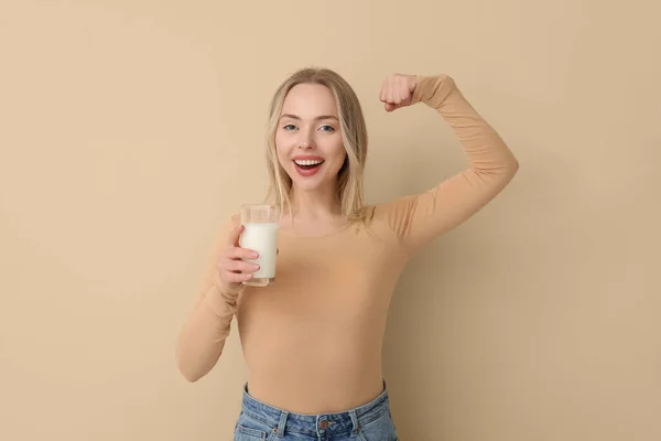 Νεαρή Γυναίκα Ποτήρι Γάλα Που Δείχνει Μυς Μπεζ Φόντο — Φωτογραφία Αρχείου
