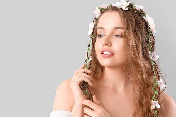 明るい背景に彼女の髪に花を持つ美しい若い女性 — ストック写真
