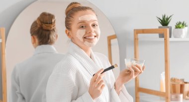 Zerdeçal maskeli ve banyoda fırçası olan güzel genç bir kadın.