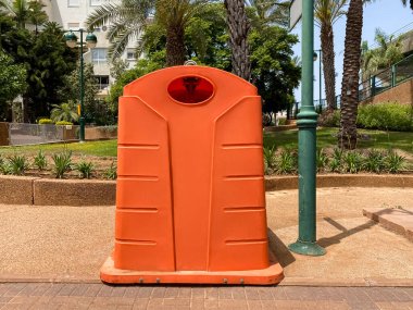 Orange garbage container on city street