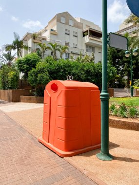 Orange garbage container on city street
