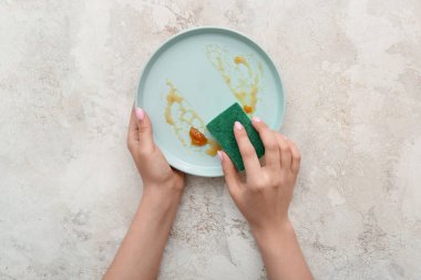 Beyaz grunge arka planda kirli tabakları süngerle yıkayan kadın elleri