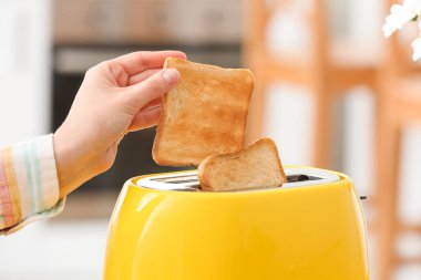 Çağdaş tost makinesinden çıtır ekmek dilimi alan kadın, yakın plan.