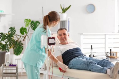 Klinikte olgun donörden kan alan kadın hemşire.