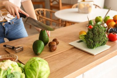 Mutfakta avokado kesen genç bir kadın, yakın plan.