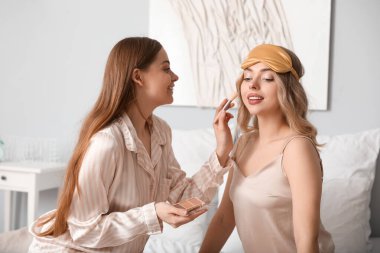 Genç kız kardeşler yatak odasında makyaj yapıyor.