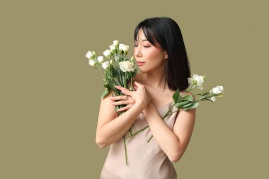 Güzel Asyalı kadın elinde renk arka planında bir buket östoma çiçeği tutuyor.