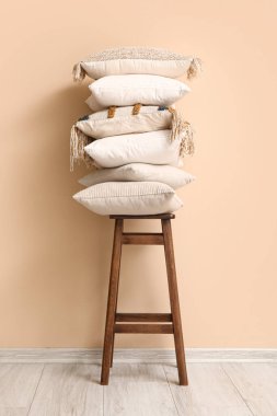 Bej duvarın yanındaki taburede şık yastıklar