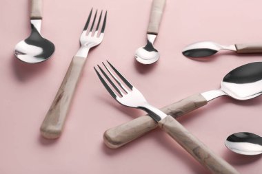 Pembe arka planda şık çatallar ve kaşıklar