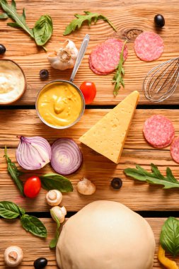 Çiğ hamur ve ahşap arka planda pizza hazırlamak için malzemeler.