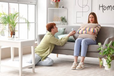 Genç adam evde düşünceli kız arkadaşına evlenme teklif ediyor.