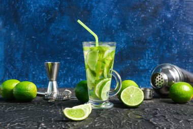 Bir bardak soğuk mojito ve sallanan limonlu siyah masa.